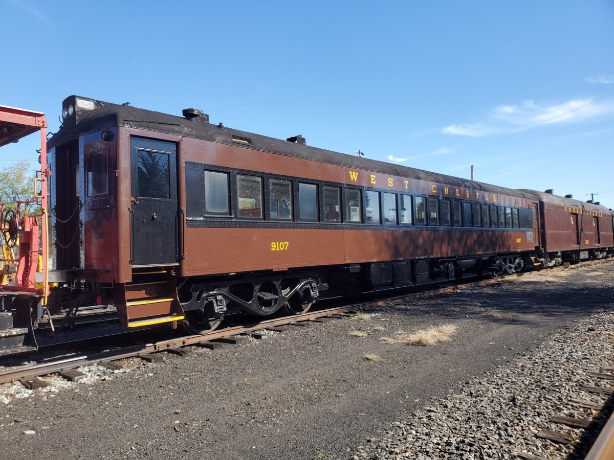 Vintage brown train car on tracks under clear sky.