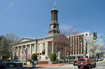 Historic courthouse with clock tower, trees, and street scene.