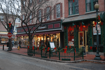 Festively decorated storefront with holiday lights and greenery on a city street corner.