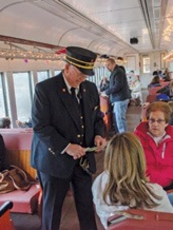 Train conductor checking tickets in a decorated passenger car.