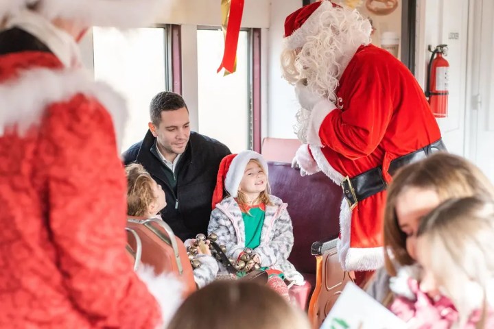 Santa Claus talking to smiling child in a festive setting.