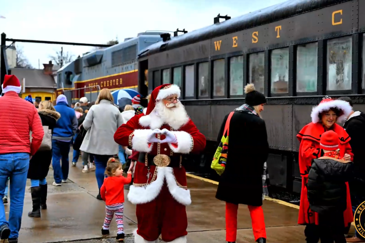 Santa and people in festive attire at a train station.