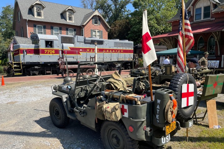 Vintage military jeep and train at an outdoor event with historical displays.